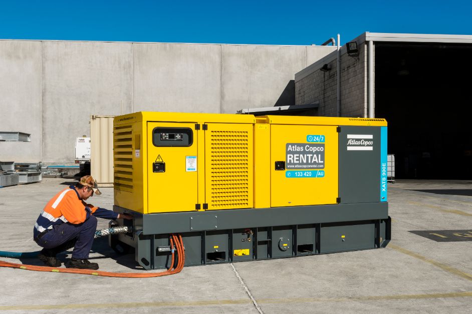 Comp4mfg technician installing an Atlas Copco air compressor rental on-site. Rental Air Compressor. Compressors For Manufacturing.  